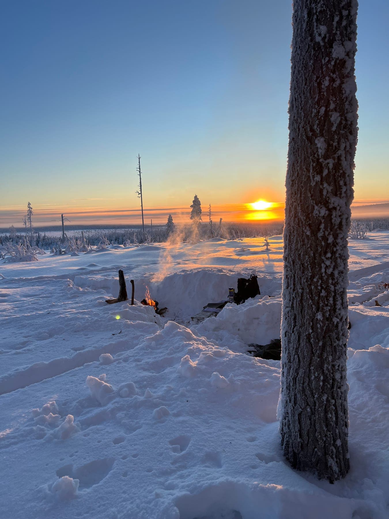 Eldstad i djup snö på bergstoppen ovanför campen, med vid utsikt över vinterlandskapet